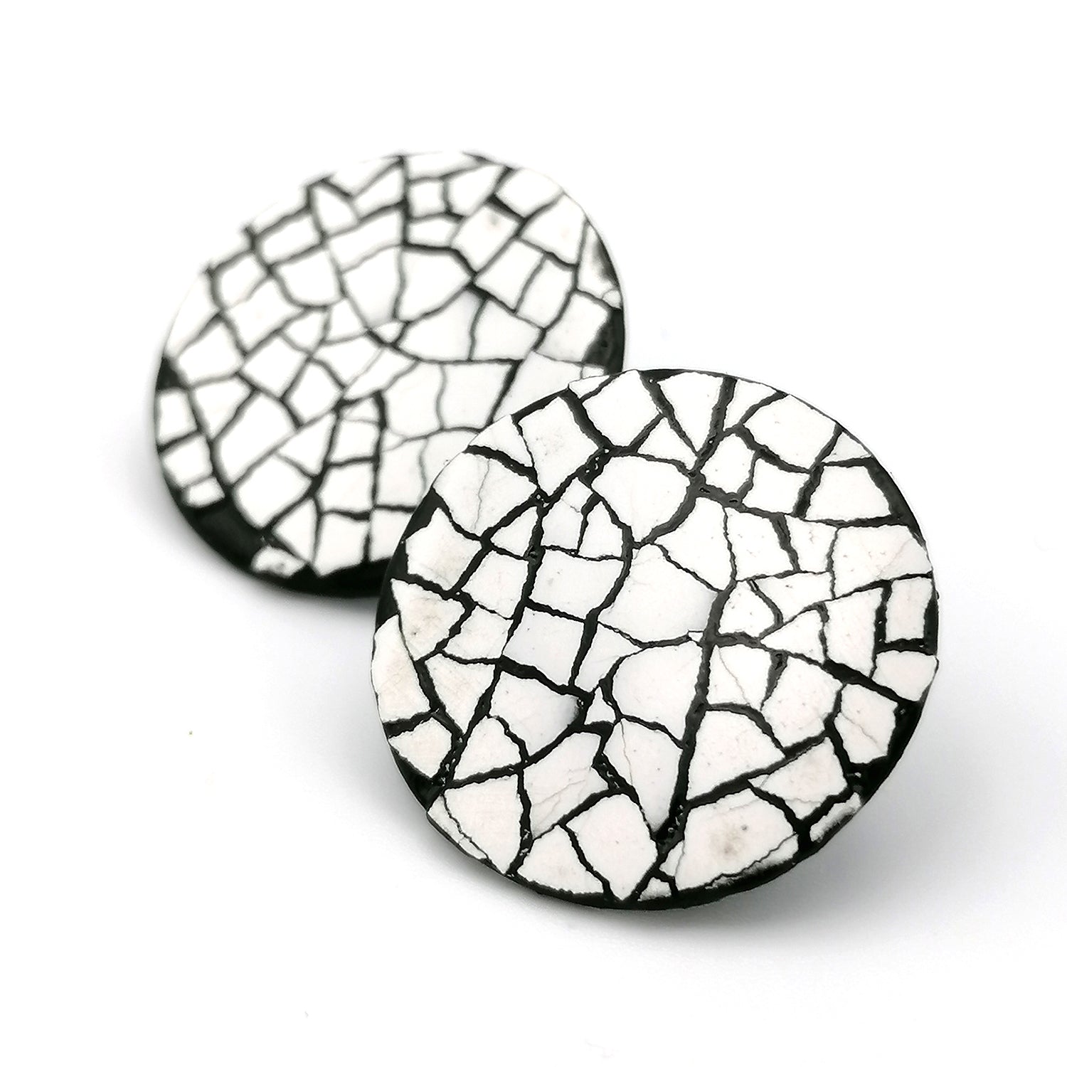 Image shows two midi modern mosaic circle stud earrings. the mosaic is made up of white real eggshell on layers of black lacquer.