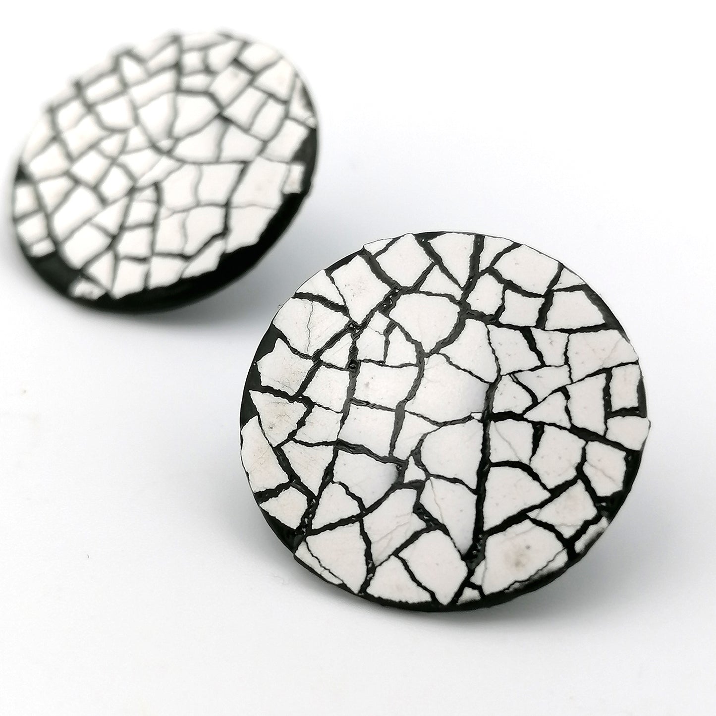 Image shows two midi modern mosaic circle stud earrings. the mosaic is made up of white real eggshell on layers of black lacquer.