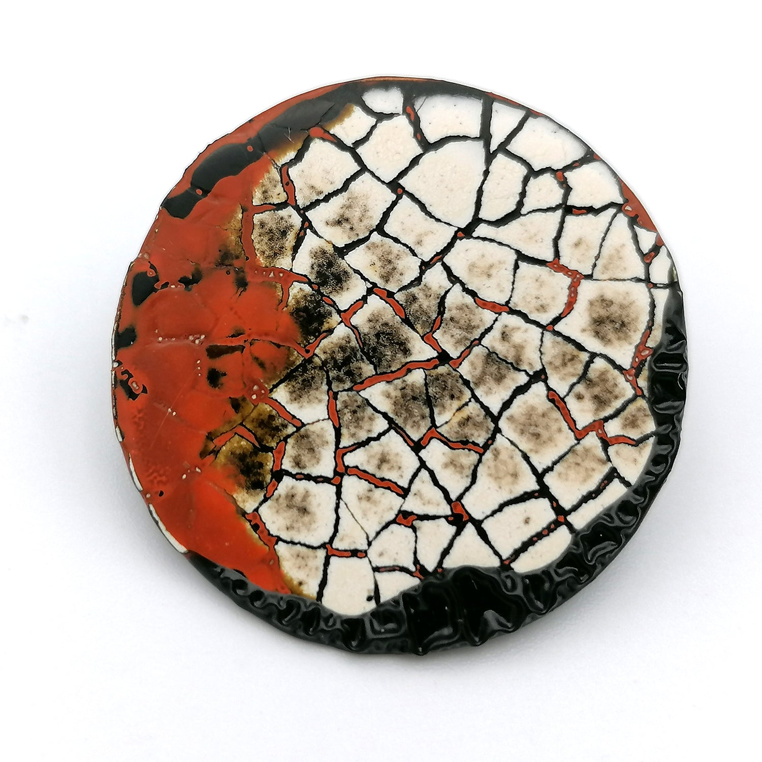 Images shows a single round stud earring on a white background. Modern mosaic earrings made out of real eggshell and black lacquer with an area of raised black wrinkled texture and patches of red.