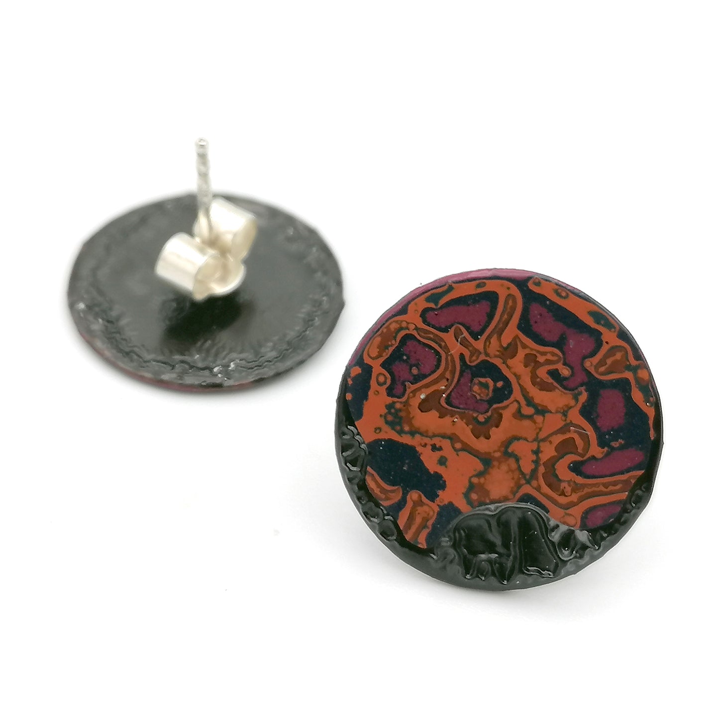 Image shows a pair of small circle stud earrings on a white background, the second of which is upside down showing the sterling silver earring post. An abstract pattern in pink, orange and blue.